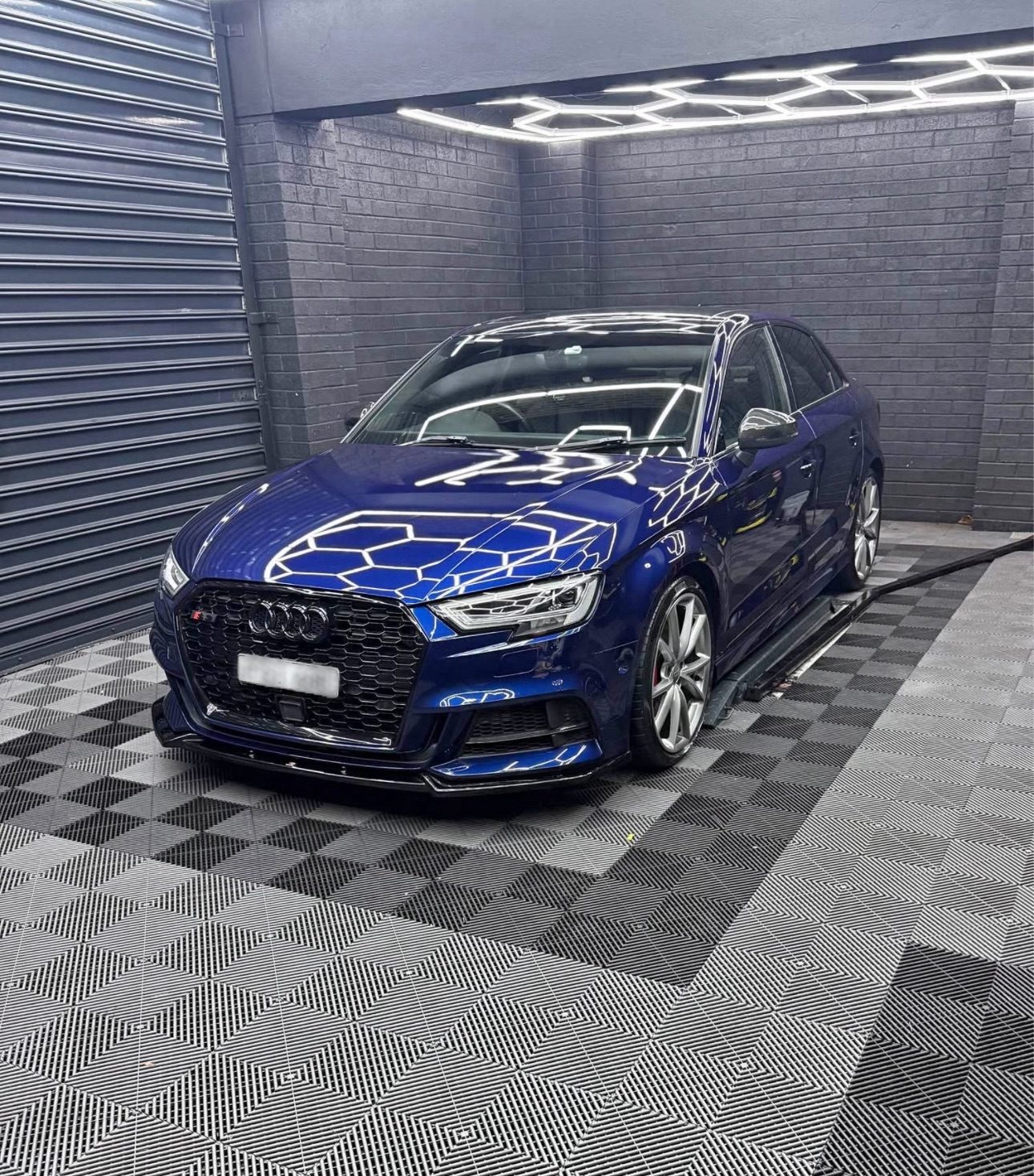 Blue Audi S3 in dark grey checkerboard workshop