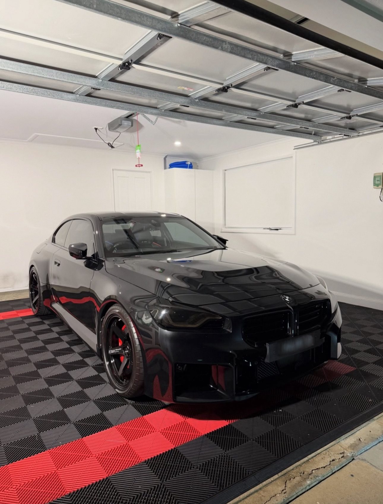 Black BMW M car on black and red racing stripe tiles