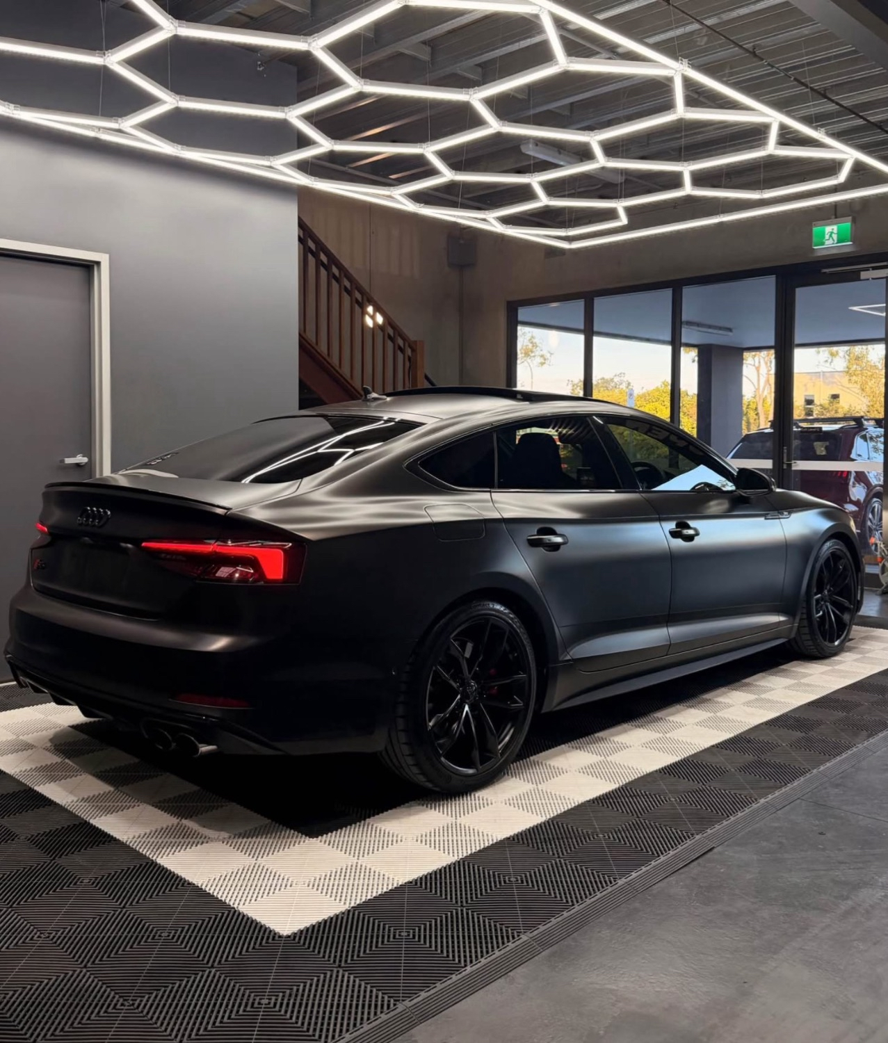 Matte black Audi RS5 in showroom with hexagon ceiling lighting