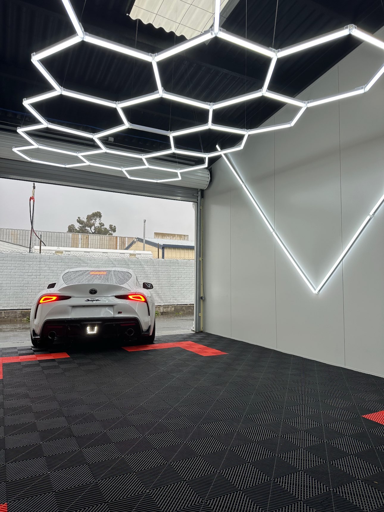 Toyota GR Supra in garage with hexagon ceiling lights and custom wall feature